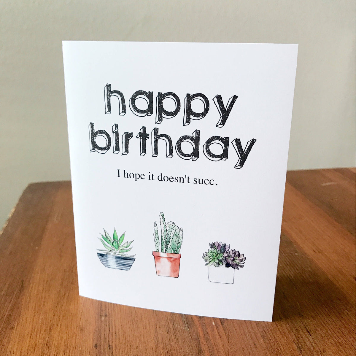 Greeting card with 'Happy Birthday' text and a humorous phrase 'I hope it doesn't succ.' followed by a drawing of three potted plants.
